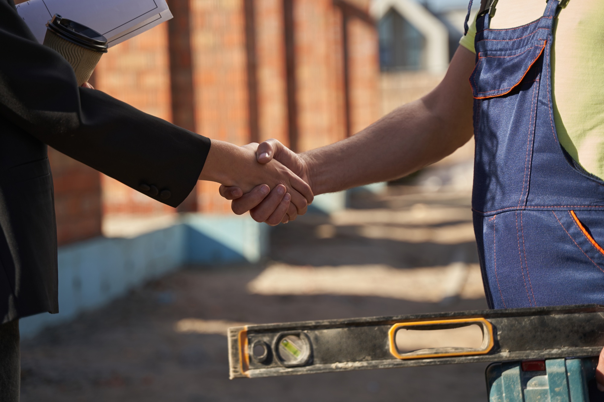 Civil engineer and worker shaking hands on site